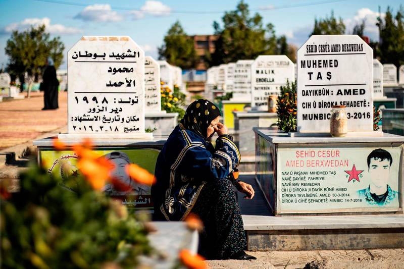 A woman mourns amidst tombs next to a funeral (unseen) for two Syrian Democratic Forces (SDF) fighters in the Syrian Kurdish-majority city of Qamishli, on January 13, 2020, after they were killed by a Turkish military drone, according to Kurdish security officials. / AFP / Delil SOULEIMAN
