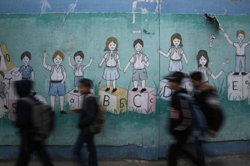 Palestinian children walk past a mural on their way to their United Nations-run school in Al-Shati refugee camp in Gaza City, on December 14, 2019. (Photo by MOHAMMED ABED / AFP)