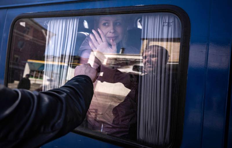 A woman waves goodbye to her husband as she leaves on a bus, a day after the rocket attack at a train station in Kramatorsk. AFP