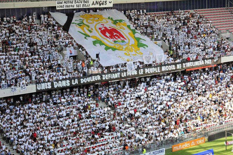People stand in the grandstands as they hold white placards in tribute to the victims of the Bastille day attack in Nice before the French Ligue 1 football match between OGC Nice and Rennes on August 14, 2016, at the Allianz Riviera stadium in Nice, southern France. Franck Pennant / AFP