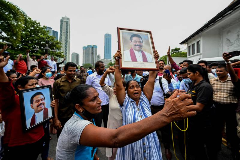 Pro-government supporters hold Prime Minister Mahinda Rajapaksa's portrait while protesting. AFP