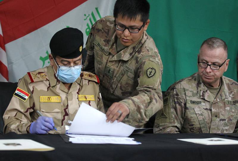 Coalition’s Brigadier General Vincent Barker (R) watches Iraq’s Staff Major General Mohammad Fadhel Abbas (L) sign a document during a pullout ceremony at the Qayyarah air base, where US-led troops in 2017 had helped Iraqis plan out the fight against the Islamic State in nearby Mosul in northern Iraq, on March 26, 2020. The 5,200 US troops stationed across Iraqi bases make up the bulk of the coalition force helping hunt down Islamic State group sleeper cells across the country. Around 300 coalition troops left the western Qaim base in mid-March, handing it over in full to Iraqi troops. Today, more troops were set to leave. In the coming weeks, they will also leave the expansive base in Kirkuk.
 / AFP / AHMAD AL-RUBAYE
