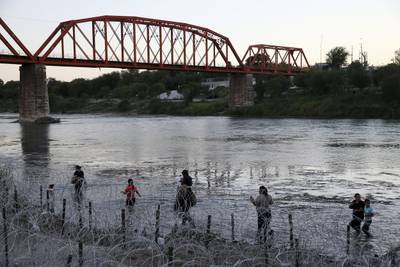 Migrants walk the Rio Grande searching for a way through the concertina wire and into the U. S.  at Eagle Pass, Texas. AP