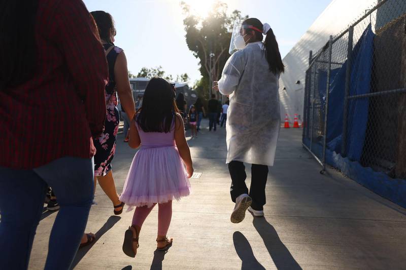 A USC research team member walks with a family after recruiting them to participate in a rapid antigen testing program at a walk-up Covid-19 testing site in San Fernando, California. AFP