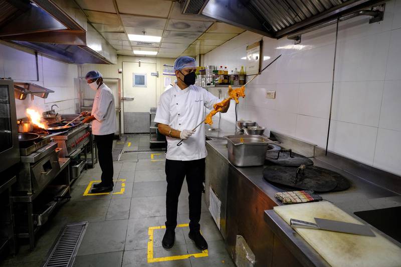 Chefs prepare food as they stand in boxes marked out to assist social distancing in the kitchen at the Punjab Grill restaurant in New Delhi, India, on Monday, June 8, 2020. Indian stocks pared gains driven by initial optimism as the country entered the first phase of opening up its economy, with hotels, restaurants and shopping malls permitted to function after more than two months of lockdown. Photographer: T. Narayan/Bloomberg