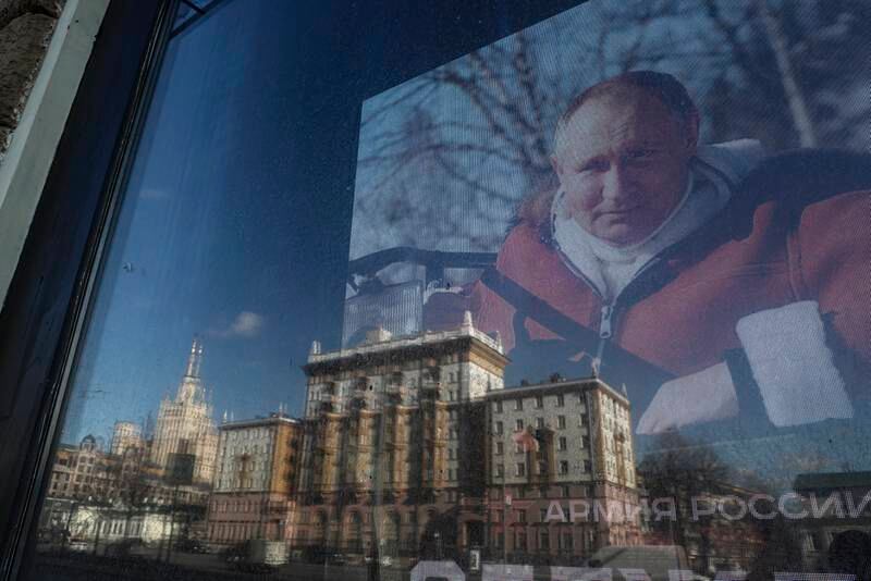 The US Embassy is reflected in a store window showing a photo of Russian President Vladimir Putin in Moscow on Monday. EPA