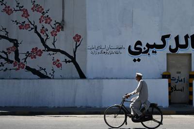 An Afghan man rides a bicycle past a barrier wall in Kabul. AFP