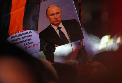 A person holds a banner of Russian President Vladimir Putin in Manezhnaya square, near Kremlin in Moscow, Sunday, March 18, 2018. An exit poll suggests that Vladimir Putin has handily won a fourth term as Russia's president, adding six more years in the Kremlin for the man who has led the world's largest country for all of the 21st century. (AP Photo/Pavel Golovkin)