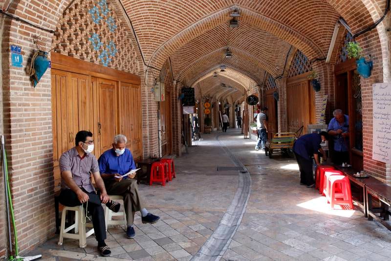 Iranians sit next to their closed shops at the old grand bazaar in Tehran.