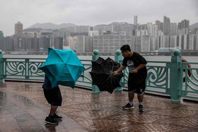 People struggle with their umbrellas in high winds brought by Typhoon Saola at Hong Kong's Victoria Harbour. AFP