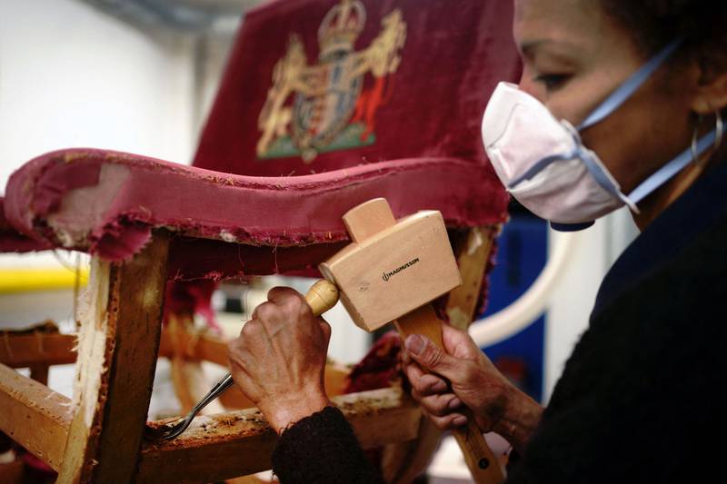Upholsterer Beatrice Ekwalla works on restoring a throne chair for the coronation at the Marlborough House workshops in London. AFP