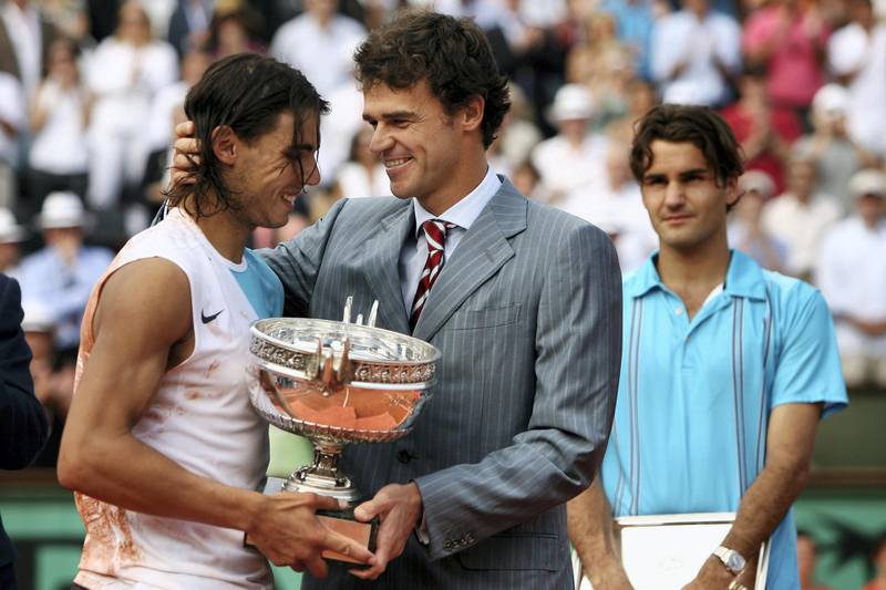 PARIS - JUNE 10:  Rafael Nadal (L) of Spain smiles as he holds the Philippe Chatrier Trophy after winning against Roger Federer (R) of Switzerland with former winner Gustavo Kuerten (C) after the Men's Singles Final on day fifteen of the French Open at Roland Garros on June 10, 2007 in Paris, France.  (Photo by Clive Brunskill/Getty Images)