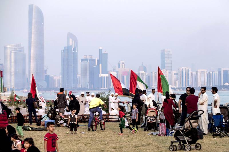 Children play along the corniche as spectators gather to watch UAE's Al-Fursan (The Knights) National Aerobatic Team performing in the capital Abu Dhabi on December 1, 2017, during celebrations ahead of the 46th Emirati National Day, celebrated on December 2. (Photo by NEZAR BALOUT / AFP)