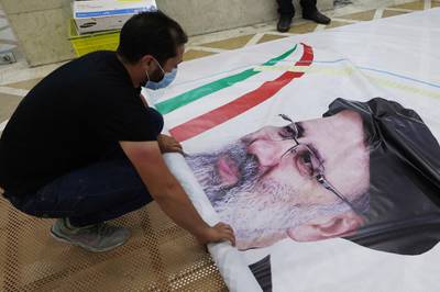 A worker prepares a campaign banner of presidential candidate Ebrahim Raisi at a print shop in the Iranian capital Tehran on June 7, 2021. Iranians are set to elect a successor to President Hassan Rouhani on June 18 amid widespread discontent over a deep economic and social crisis caused by the reimposition of crippling sanctions after the US pulled out of the 2015 nuclear deal. / AFP / ATTA KENARE
