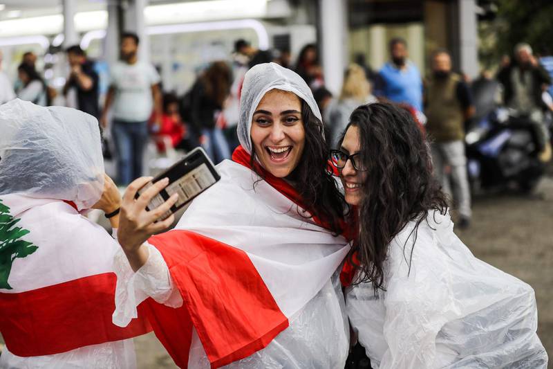 Protesters pose for a "selfie" on a cell phone under the rain during in Zouk Mosbeh. AFP
