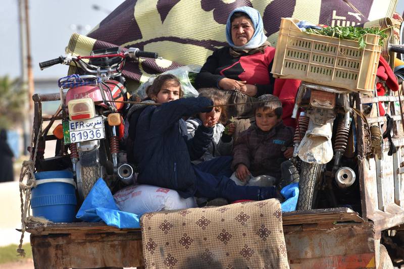 Civilians fleeing the city of Afrin in northern Syria are seen on the back of a pick up truck as they enter the town of Tal Rifaat in the government-controlled part of the northern Aleppo province, on March 18, 2018. George Ourfalian / AFP