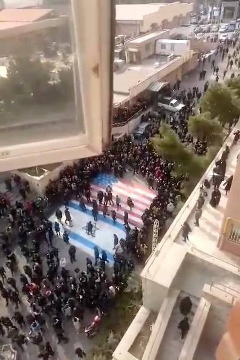 Several people walk on US and Israeli flags while others avoid stepping on the flags by walking around them, at the Shahid Beheshti University in Tehran, Iran.  Reuters.