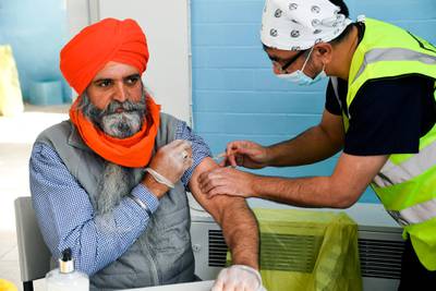Dr Manraj Barhey administers a dose of AstraZeneca vaccine to Baltjit Singh, at the Guru Nanak Gurdwara Sikh temple in Luton. AP Photo