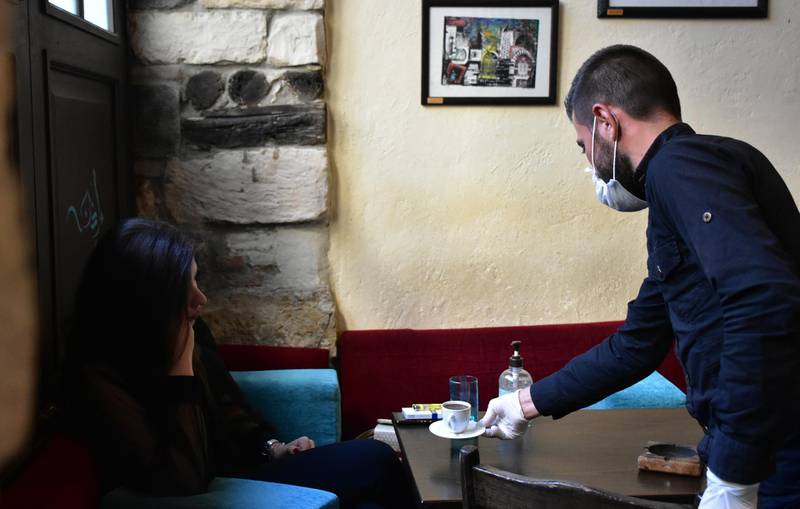 A waiter serves a cup of coffee to a customer at a cafe in Damascus, Syria.  EPA