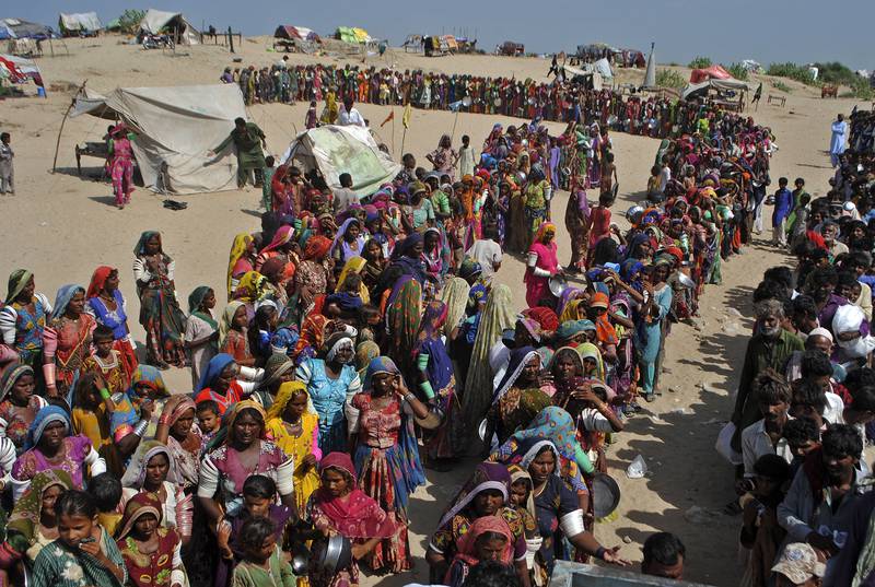People from flood-affected areas wait for food distributed by a charity in southern Sindh province, Pakistan. The country has been devastated by deadly floods amid rising global temperatures. AP
