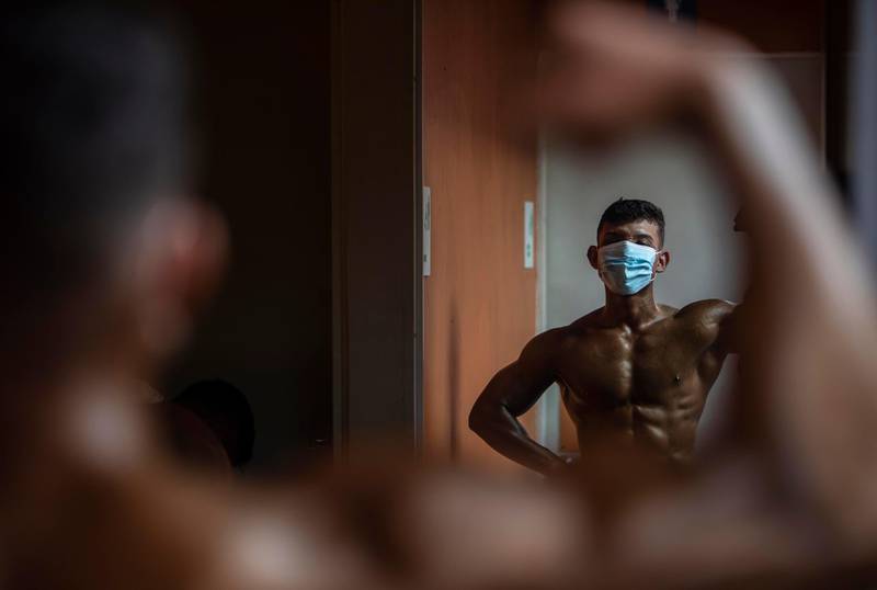A bodybuilder looks at himself on a mirror as he prepares to participate in the National Bodybuilding Championship in Managua. AFP