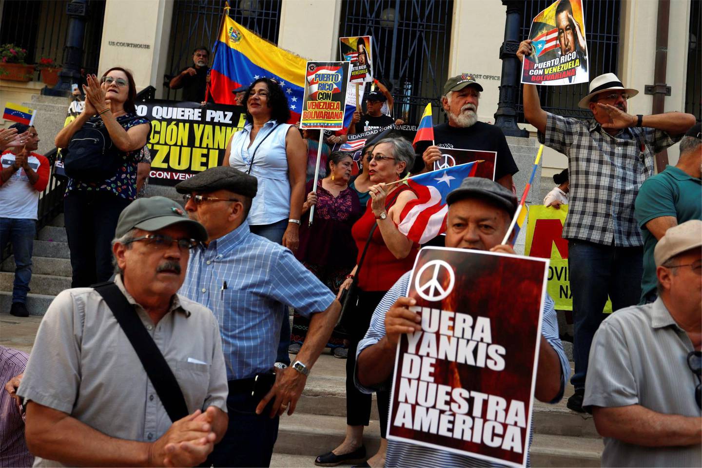 epa07371240 People hold placards and flags during a demonstration supporting the Government of Nicolas Maduro, in front of the Federal Court of Old San Juan, Puerto Rico, 14 February 2019. The demonstration also expressed their disproval of a US military intervention in the South American country.  EPA/THAIS LLORCA