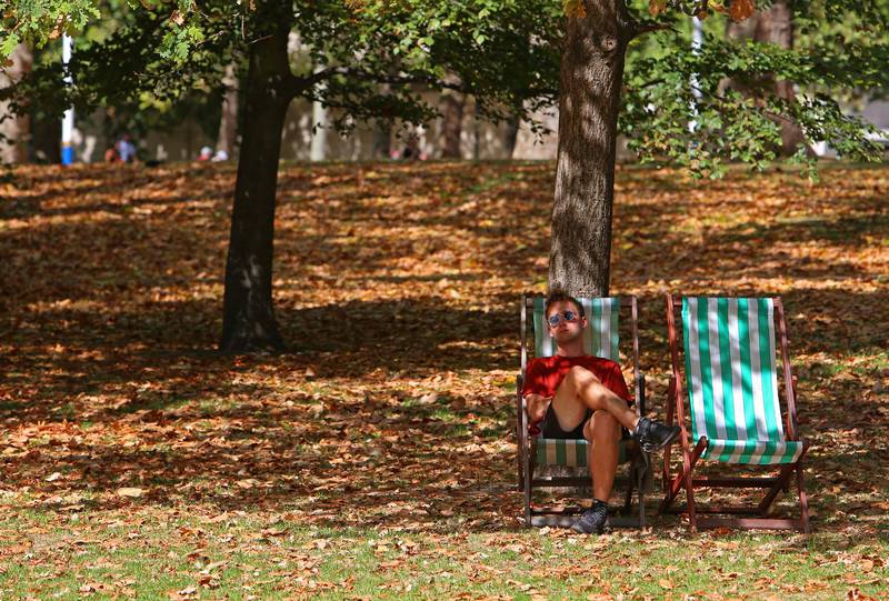 A man sits on a deckchair among brown leaves fallen from the trees in St James's Park, central London, on Wednesday. AFP