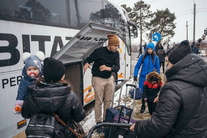 A local man helps displaced Ukrainians load their luggage into a bus after they crossed the border in Siret, Romania. Bloomberg