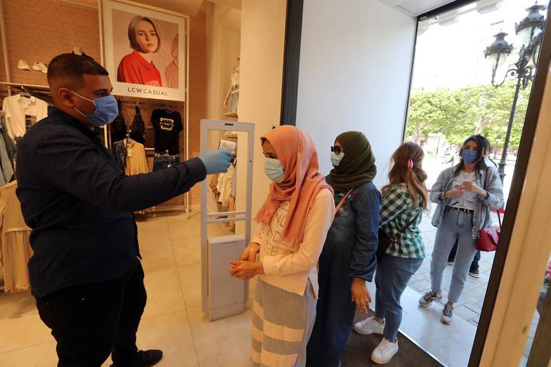 An employee checks customers' temperature upon their arrival at LC Wakiki store in Tunis, Tunisia. EPA