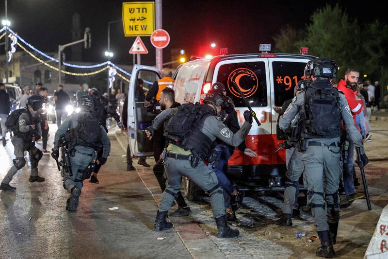 An Israeli border guard officer hits a Palestinian with a baton near an ambulance. AFP