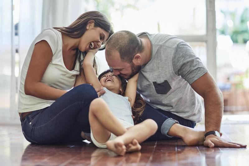 Shot of a mother and father bonding with their adorable young daughter at home