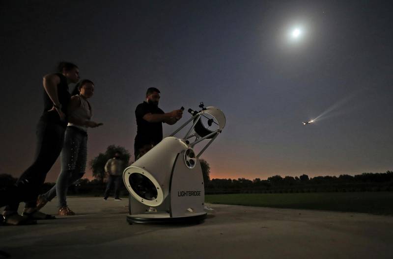 People stand to watch a partial lunar eclipse through a telescope at the Al Thuraya Astronomy Center in Dubai. AP Photo/Kamran Jebreili