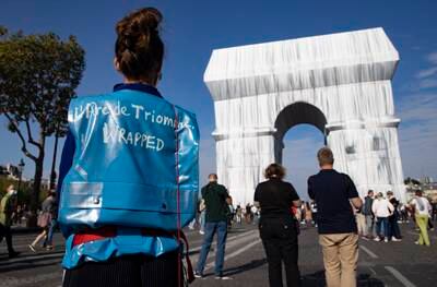 An organisation member stands before the fully wrapped Arc de Triomphe monument. EPA