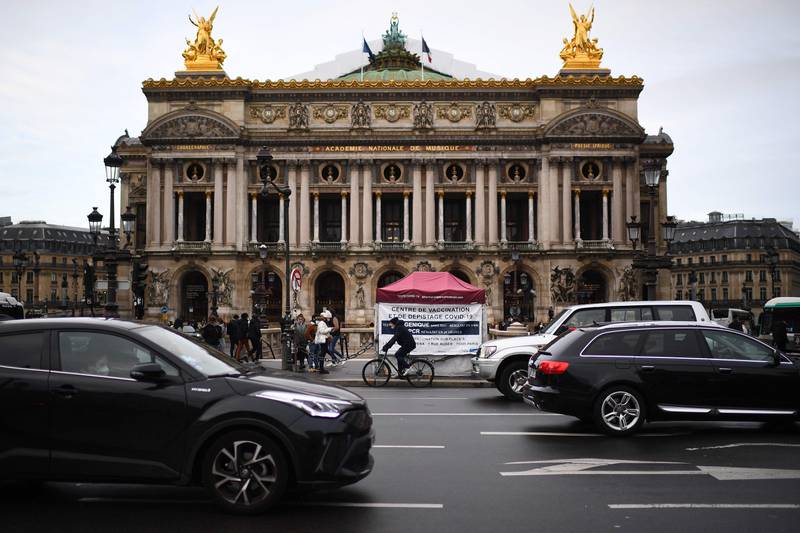 A cyclist rides past a tent where patients are undergoing coronavirus tests, at the Opera square in Paris. AFP