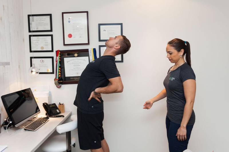 Dubai, March 16th  2016. Dr Janine McKay, achiropractor at Diversified Integrated Sports Clinic, demonstrating exercises onecan do at the work desk. This is standing supported extension. It is recommended to repeat the exercises 10 times per hour in one sitting. Anna Nielsen for The National *** Local Caption ***  Anna_Nielsen_Diversified Integrated Sports Clinic_07.JPG