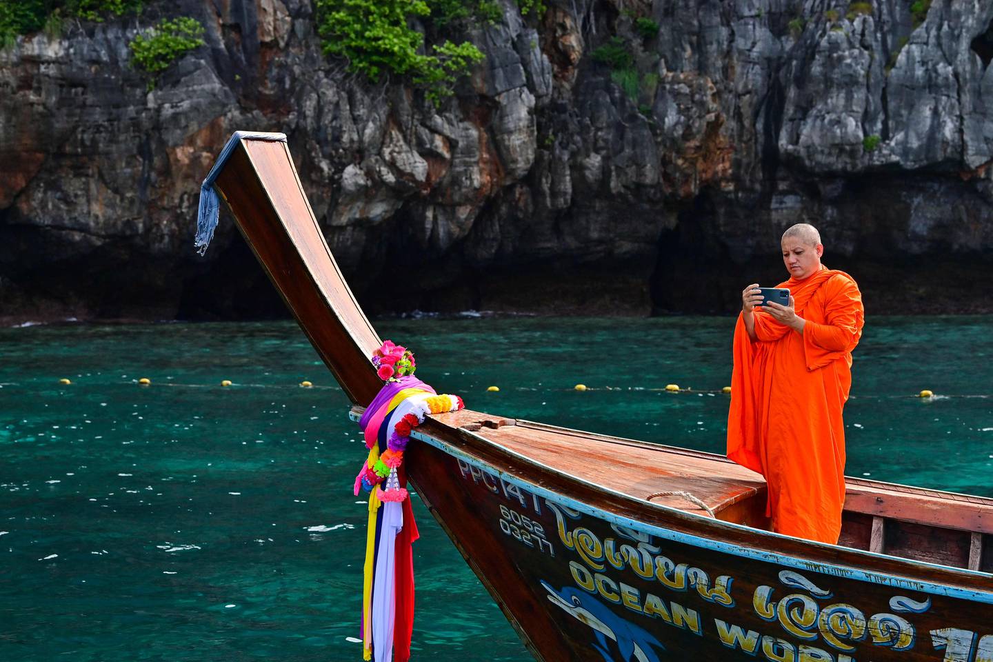 A Buddhist monk captures the views from a longtail boat in Maya Bay on Thailand's Phi Phi Leh island. AFP
