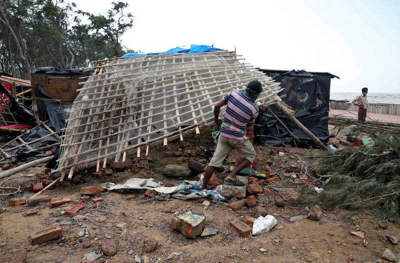 A man in West Bengal clears debris after Cyclone Yaas struck the area. Reuters