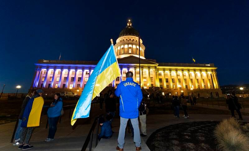 Zac Haycock stands in front of the Utah State Capitol, which is lit in blue and yellow in support of Ukraine. AP