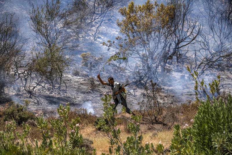 A man uses a branch to douse small fires in Ksar Sghir. AFP