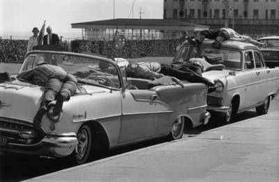 Holiday makers in Clacton-on-Sea relax in the heat by lying on top of their parked cars in 1967. 