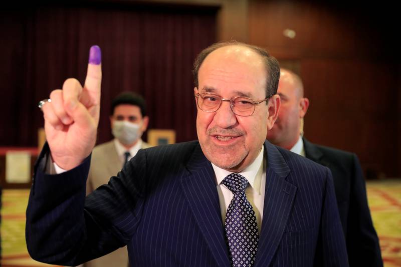 Former Iraqi Prime Minister Nouri al-Maliki shows his inked finger at a polling station in Baghdad, as Iraqis go to the poll to vote in the parliamentary election, in Iraq, October 10, 2021. REUTERS/Thaier al-Sudani