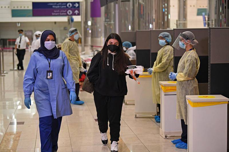 Health workers check passenger who arrived in an Emirates Airlines flight from London at Dubai International Airport. AFP