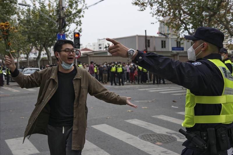 A protester holding flowers is confronted by a policeman during a protest on a street in Shanghai, China. AP