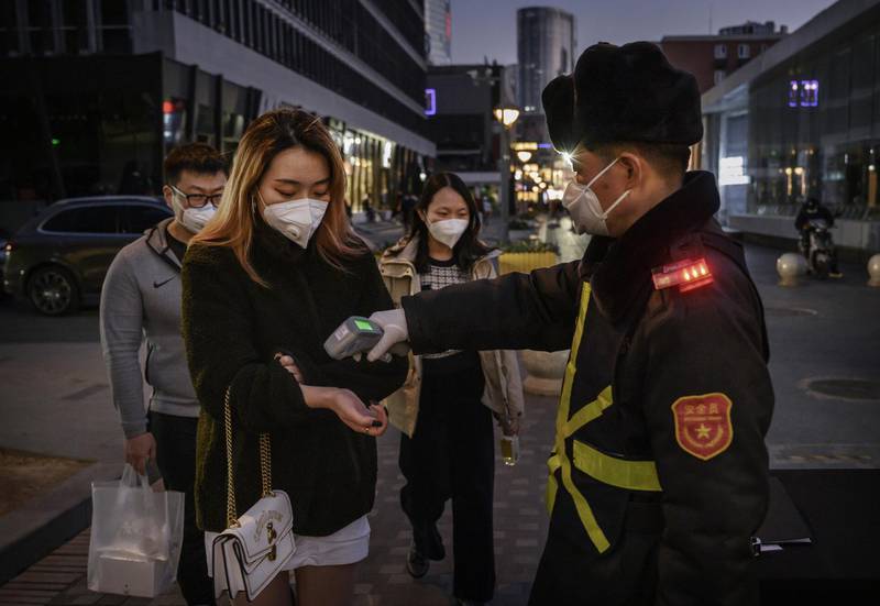 A Chinese woman wears a protective mask as she has her temperature checked by a security guard before entering a shopping area in Beijing, China. Getty Images