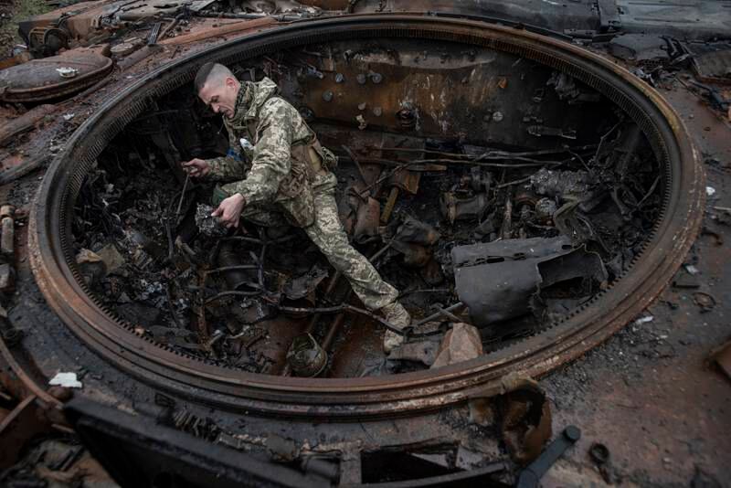 A Ukrainian soldier inspects the wreckage of a burnt Russian tank in Dmytrivka, Kyiv region. Getty Images