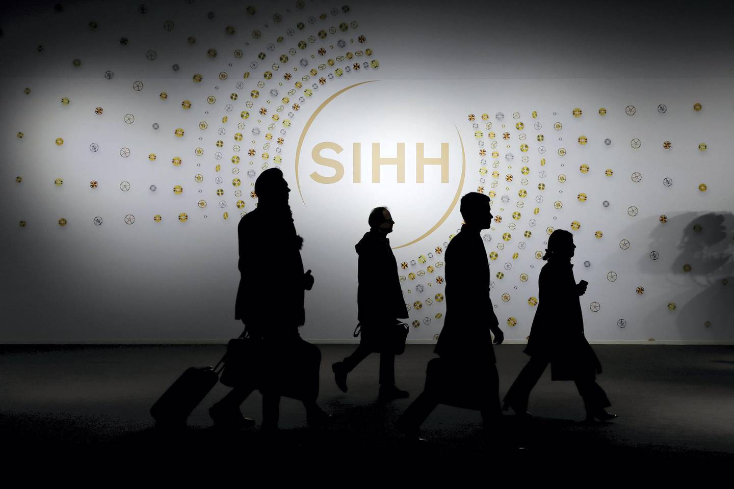 Visitors pass a show logo as they arrive for the Salon International de la Haute Horlogerie (SIHH) in Geneva, Switzerland, on Tuesday, Jan. 15, 2019. The elephant in the room at this week’s Swiss watch fair in Geneva is that the industry is still struggling to find buyers for all the timepieces it has produced over the years. Photographer: Stefan Wermuth/Bloomberg