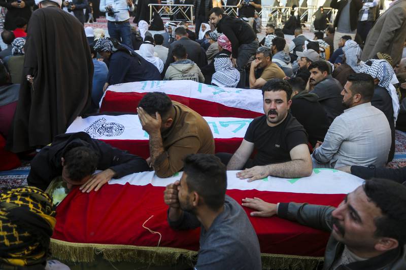 Iraqis mourn next to the coffins of victims of a militant attack, in a village west of Baghdad on Tuesday. AP