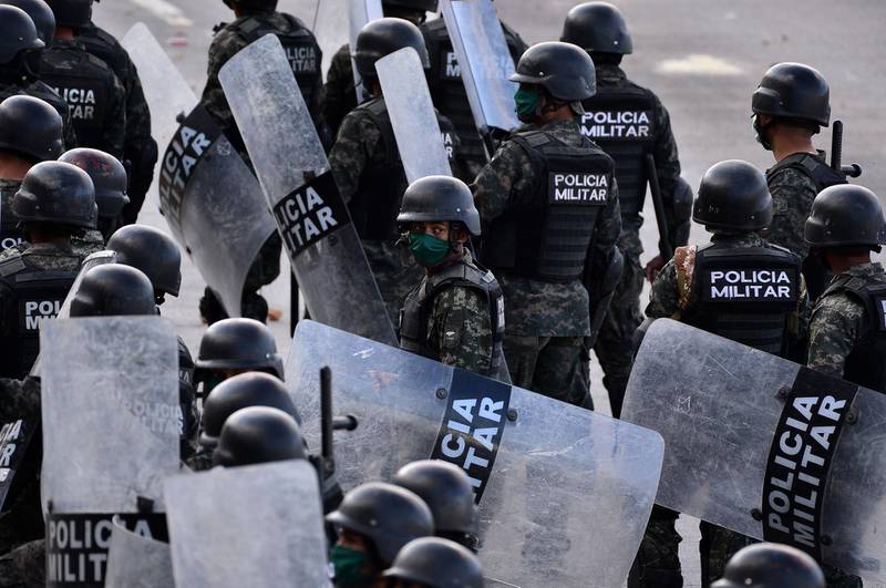 Riot police walk towards drivers and workers related to the public transport blocking a street in Tegucigalpa as they protest against "an absolute curfew" decreed by the government to force the population to isolate themselves in their homes and curb the spread of the COVID-19 coronavirus.  AFP