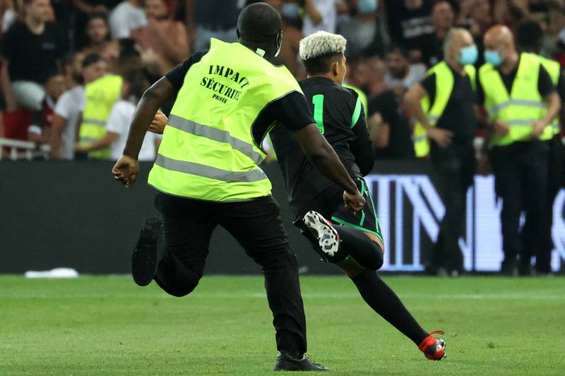 A security officer chases a fan during the pitch invasion. AFP