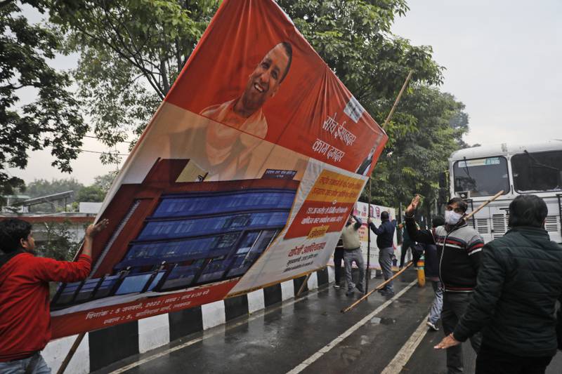 Municipal workers remove a hoarding displaying an image of Indian Prime Minister Narendra Modi and Uttar Pradesh Chief Minister Yogi Adityanath in Lucknow, Uttar Pradesh, on Saturday. Photo: AP
